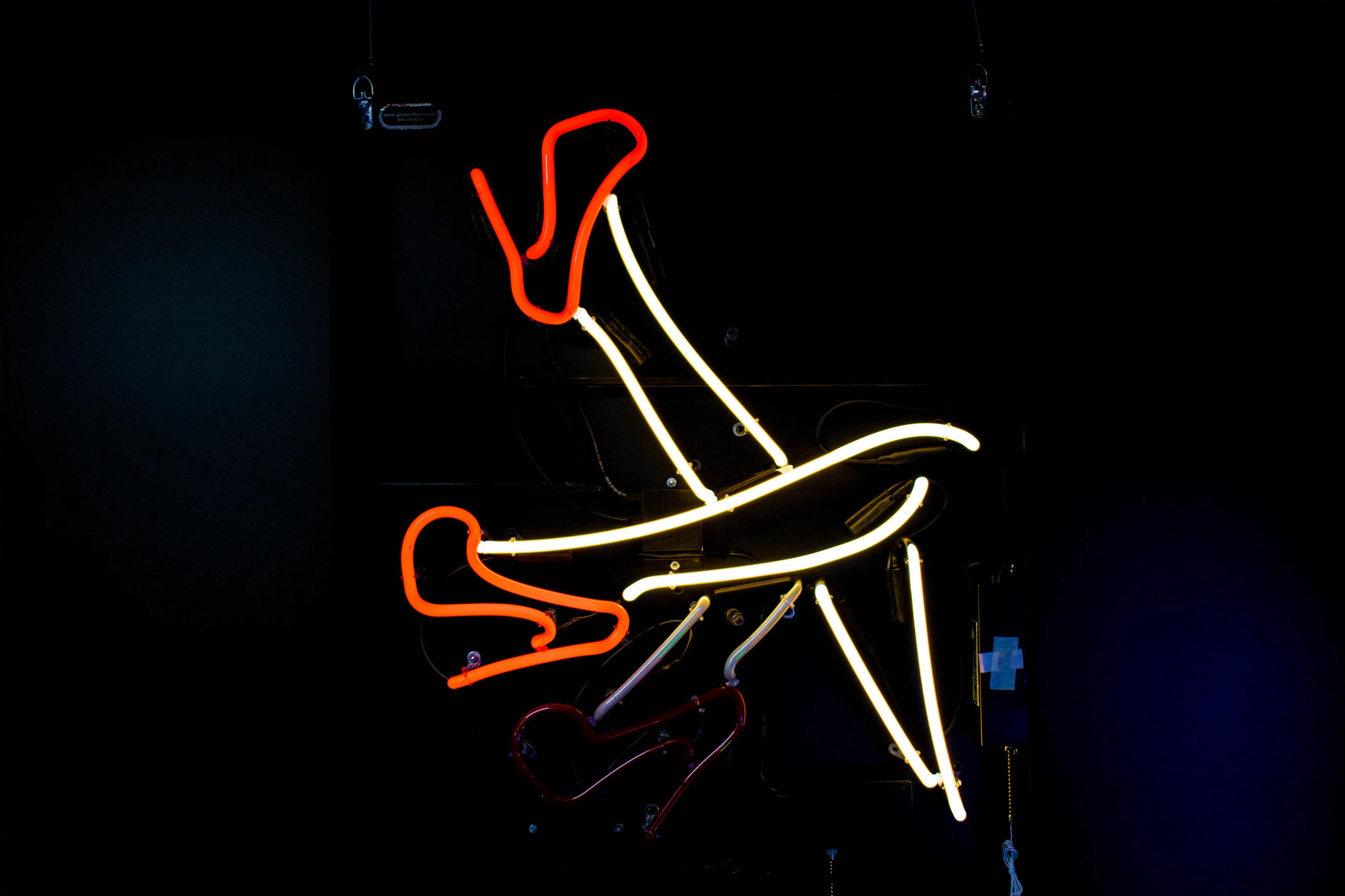 The first of three images showing a neon sign of legs kicking. 