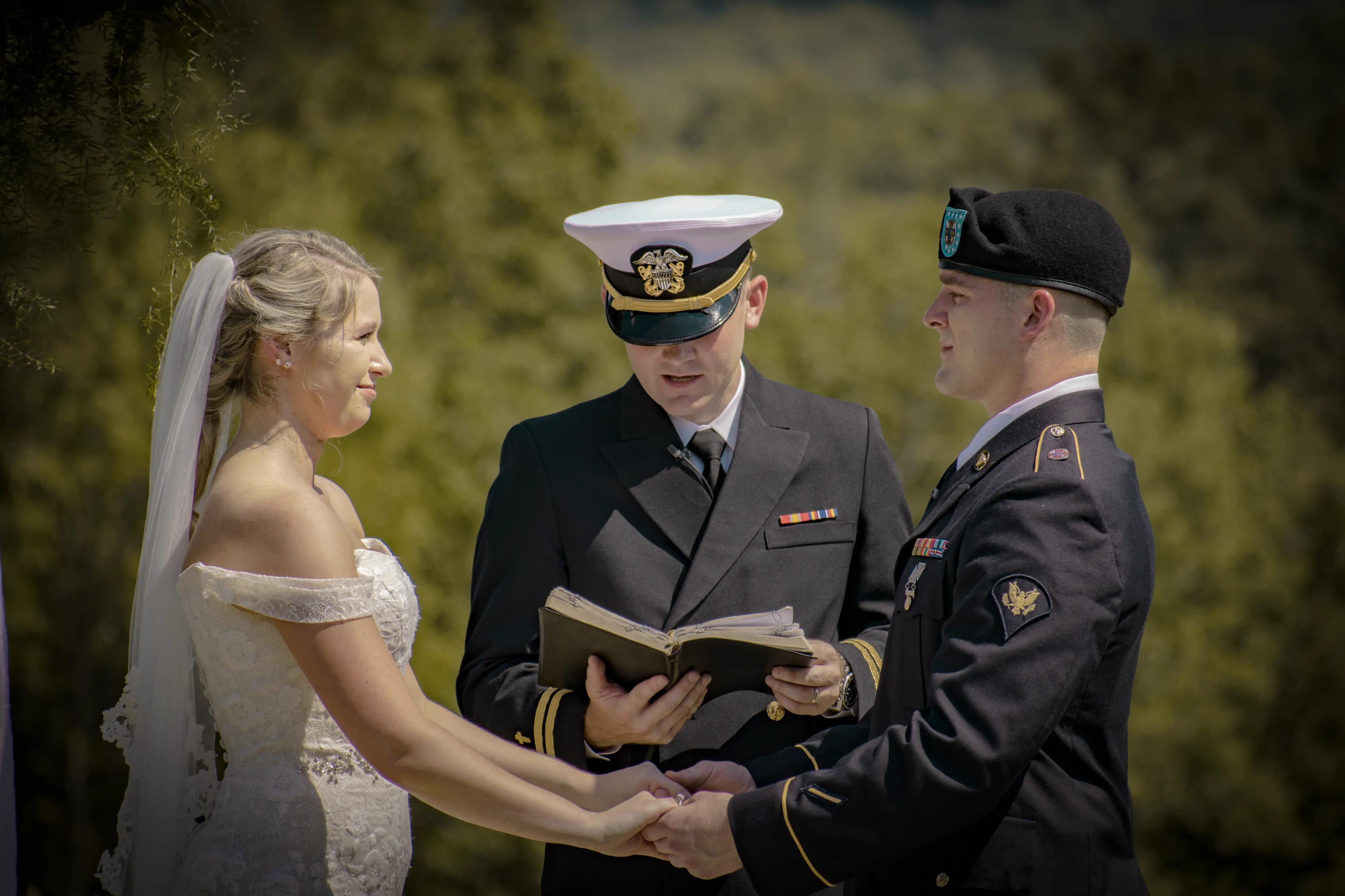 C + L holding hands during their wedding ceremony as the officiant reads out their vows.