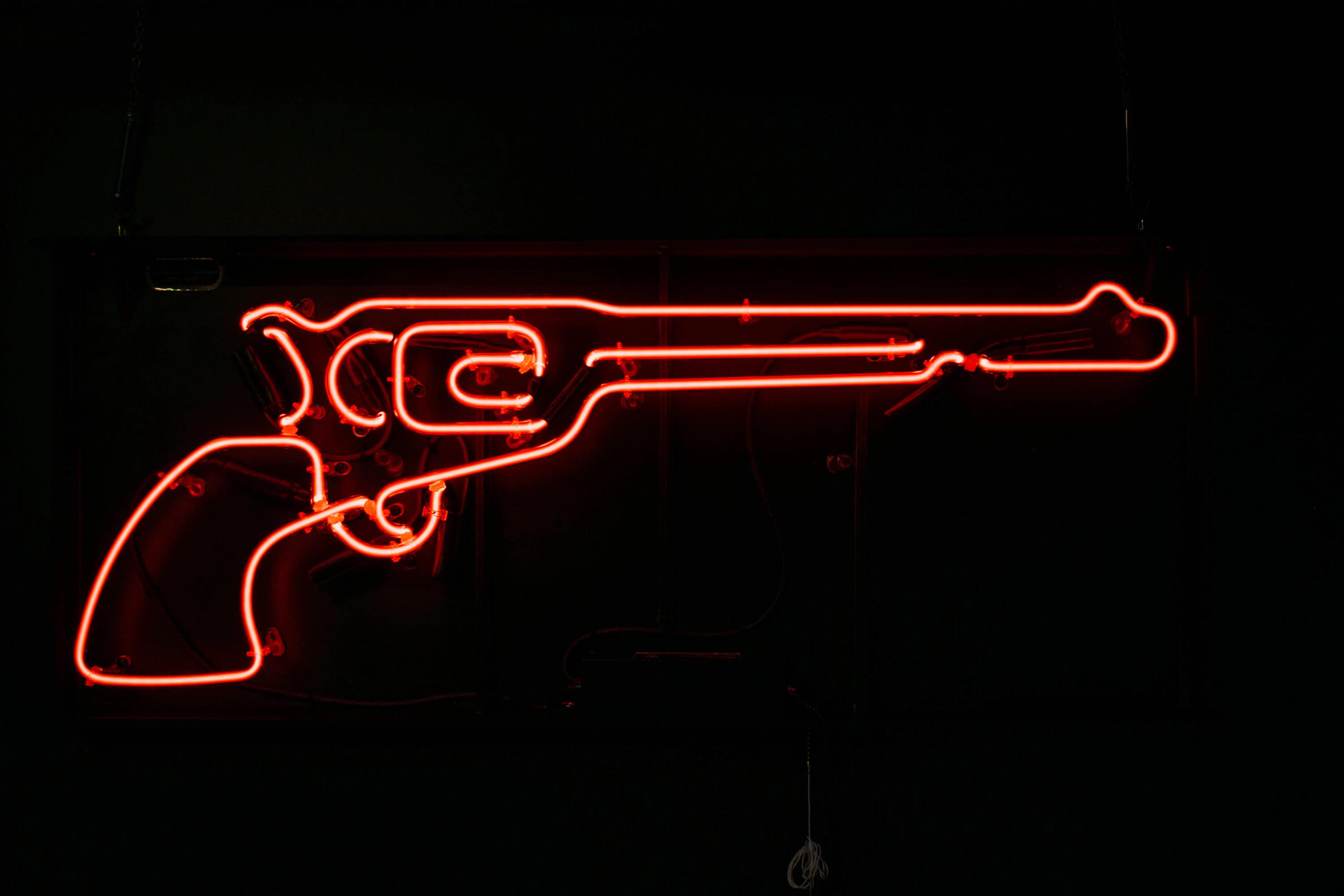 A neon sign showing a red revolver.