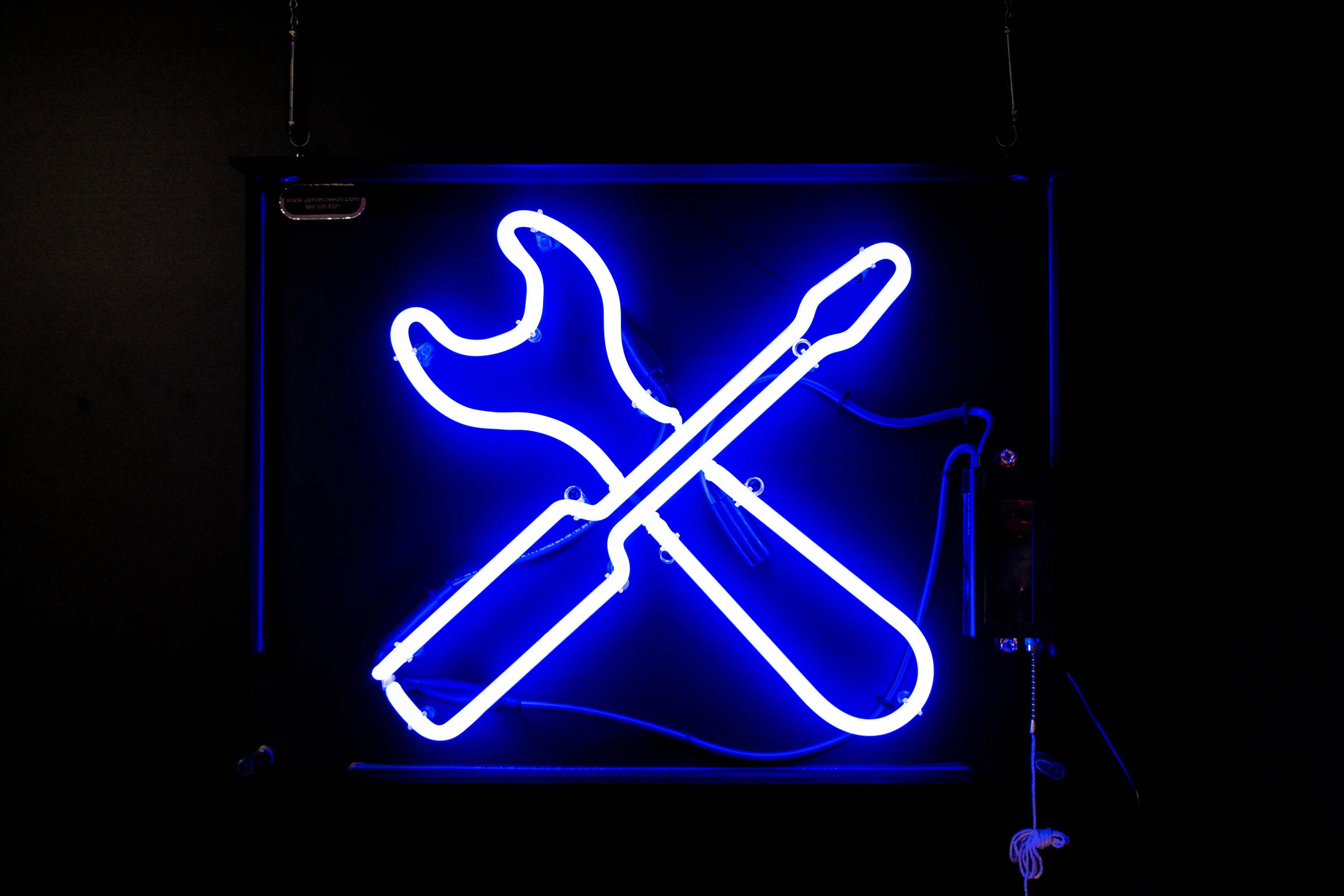 A blue neon sign of a screwdriver and wrench crossed over each other.