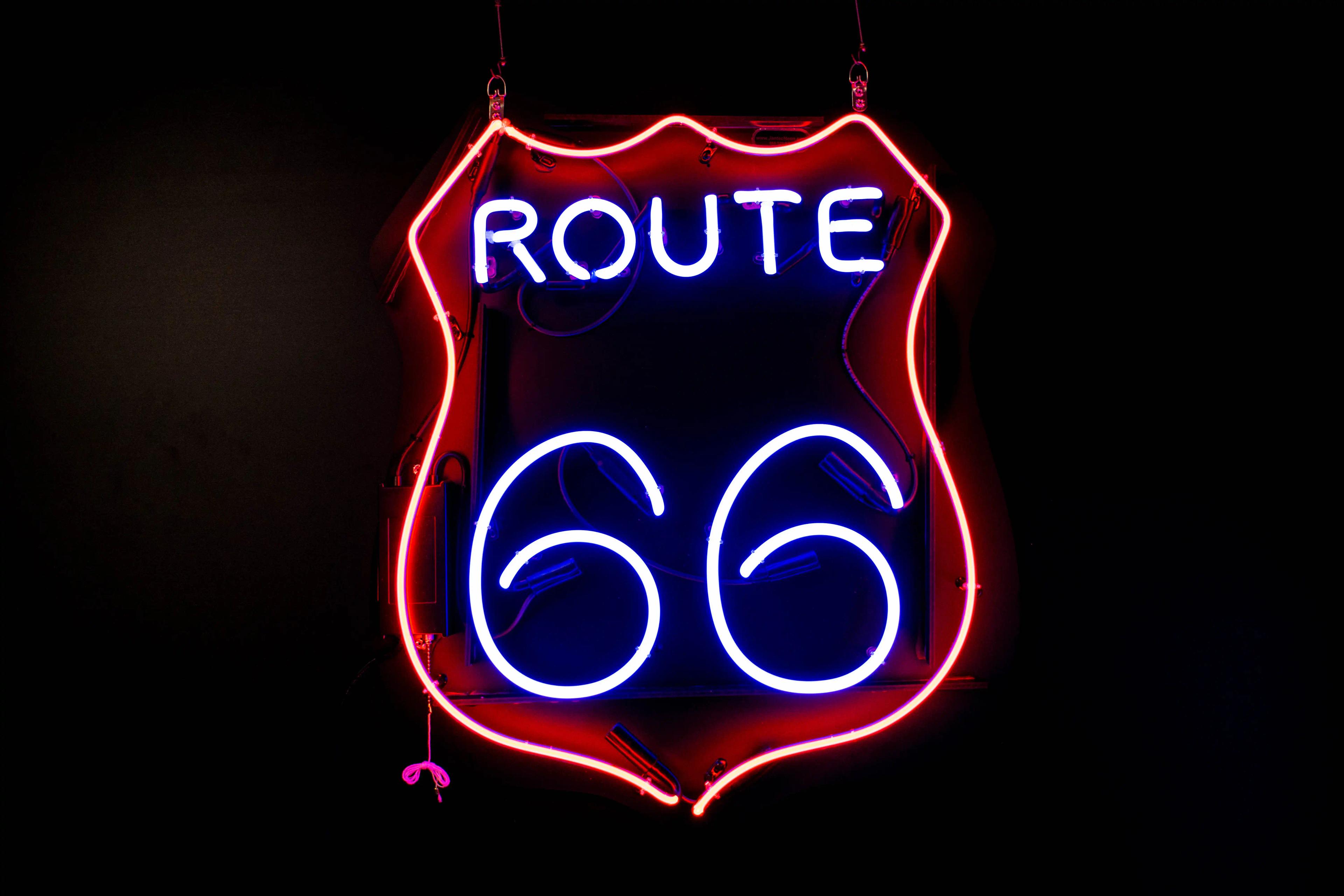 A neon sign in the style of a road sign that says route 66.