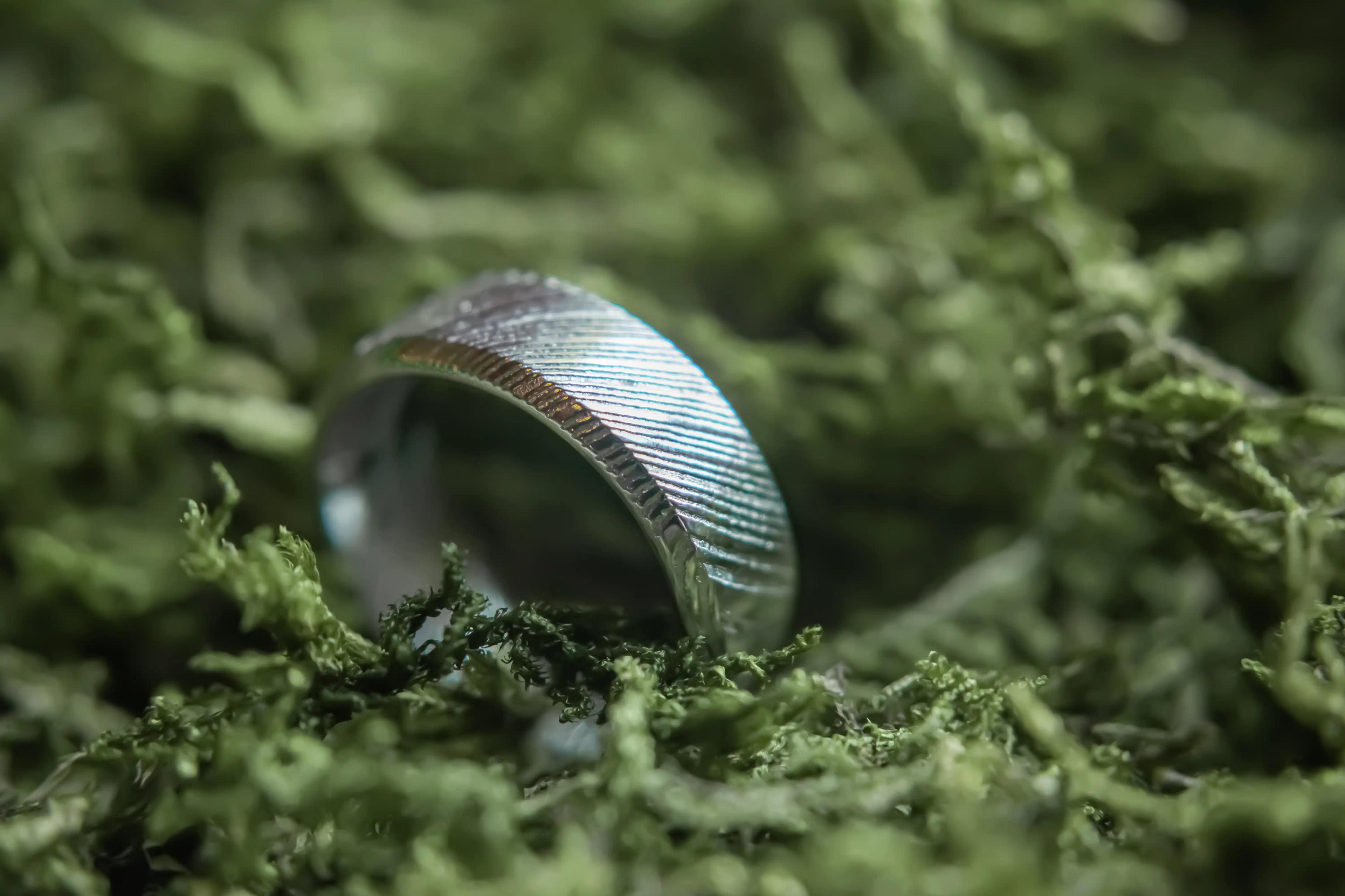 A close-up shot of the grooms ring surrounded by green foliage.