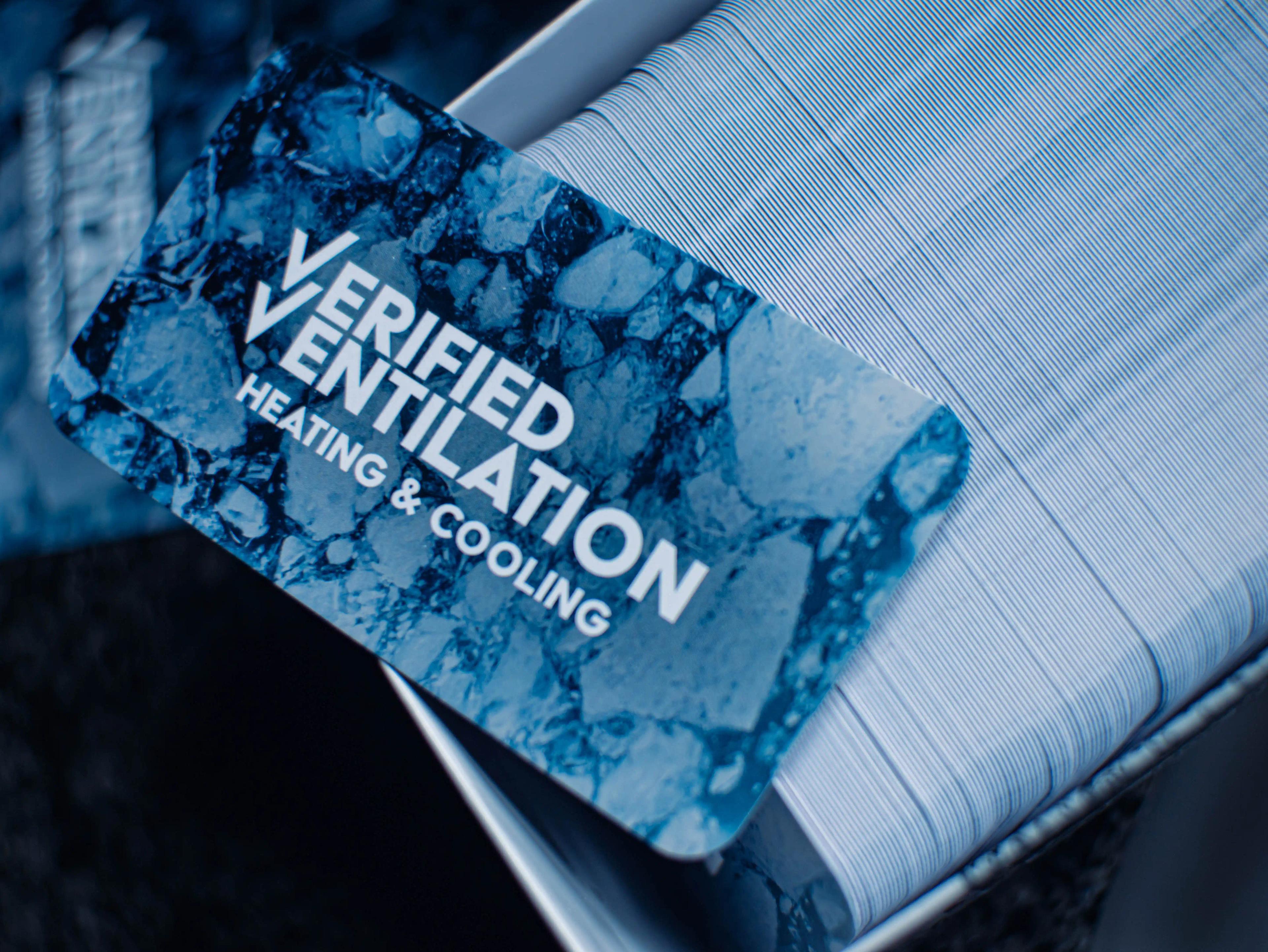 An image of Verified Ventilations business cards box full of cards with one card on top showing the front of the business card.